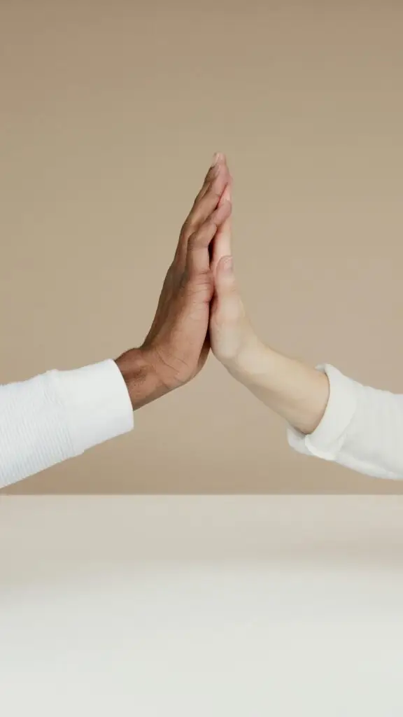 Two hands meet in a high-five, symbolizing cooperation and unity.